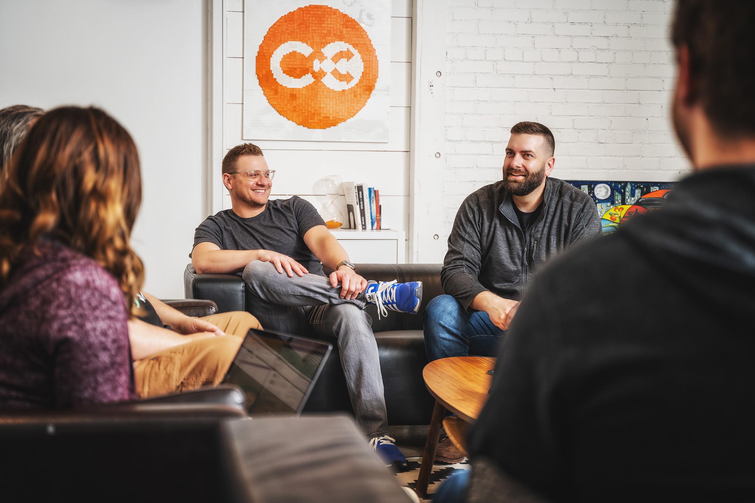 CoSchedule Co-Founders, Garrett Moon & Justin Walsh, sitting with team